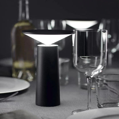 Black table lamp on a dining table with wine glasses and plates in the background