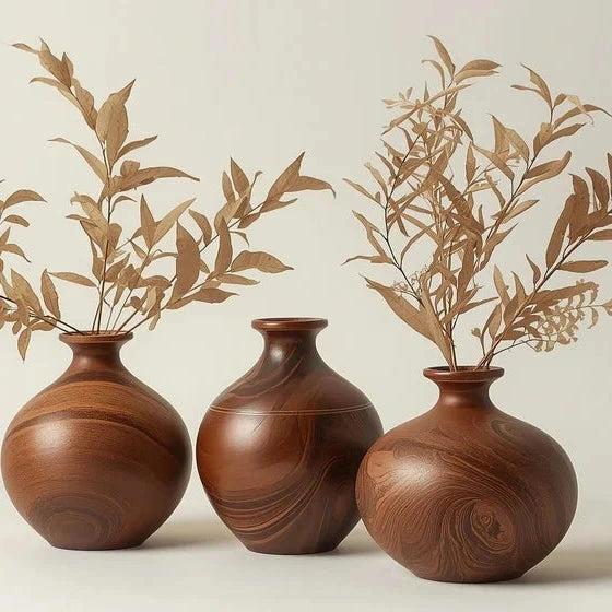 Three wooden vases with leafy branches on a light background